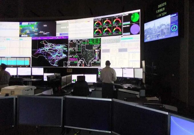 A man in front of multiple monitors.